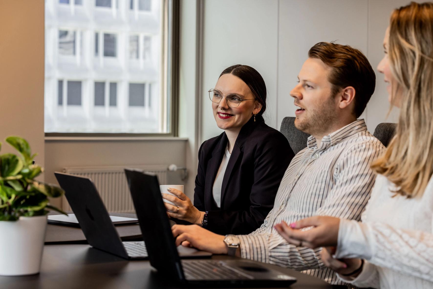 3 personer i workshop på jobb med PC, vindu, plante.
