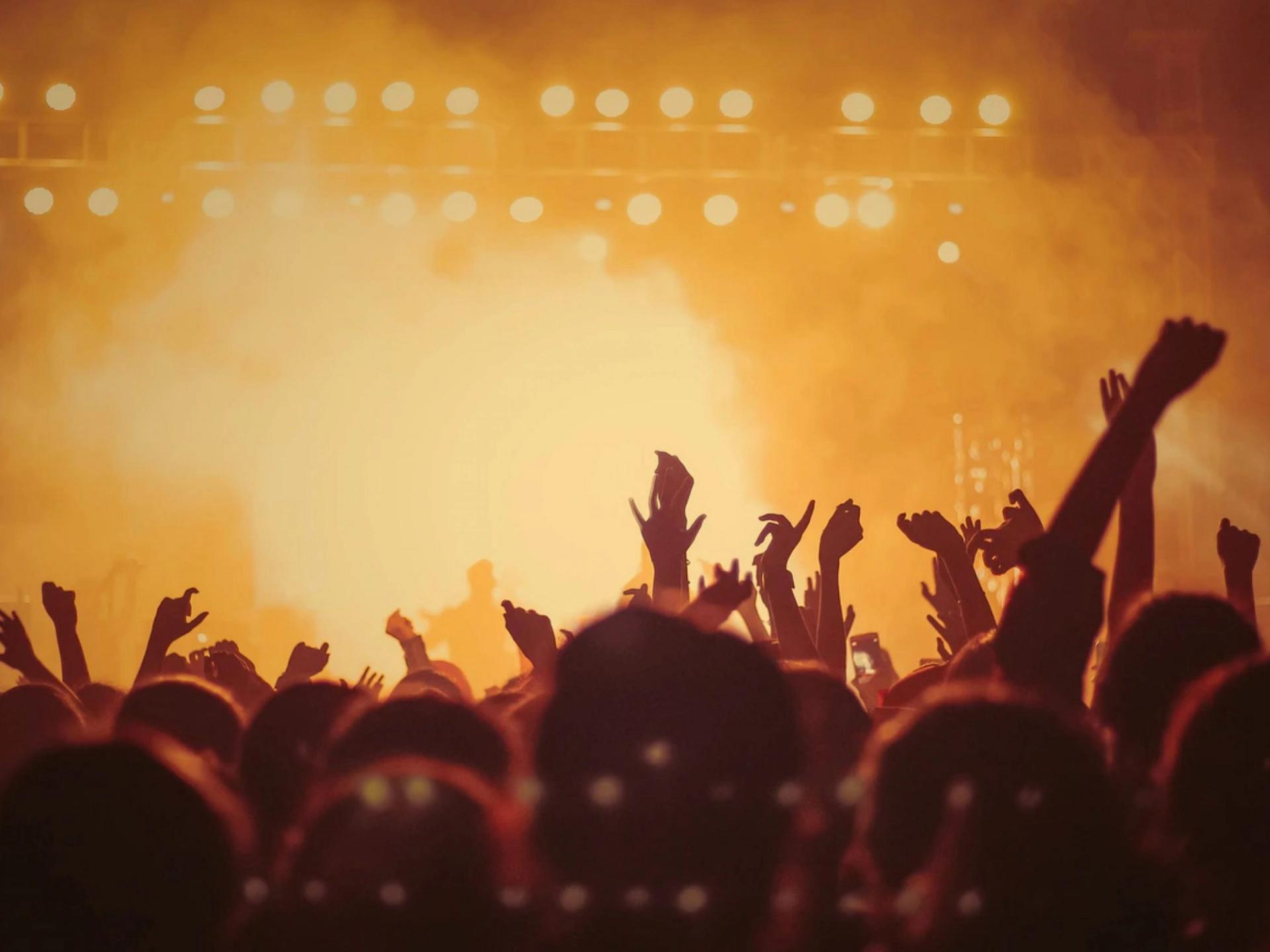 Konsertpublikum i oransje scenelys. Illustrasjon i artikkel om hvordan All Things Live bruker Lawai i HR-arbeidet