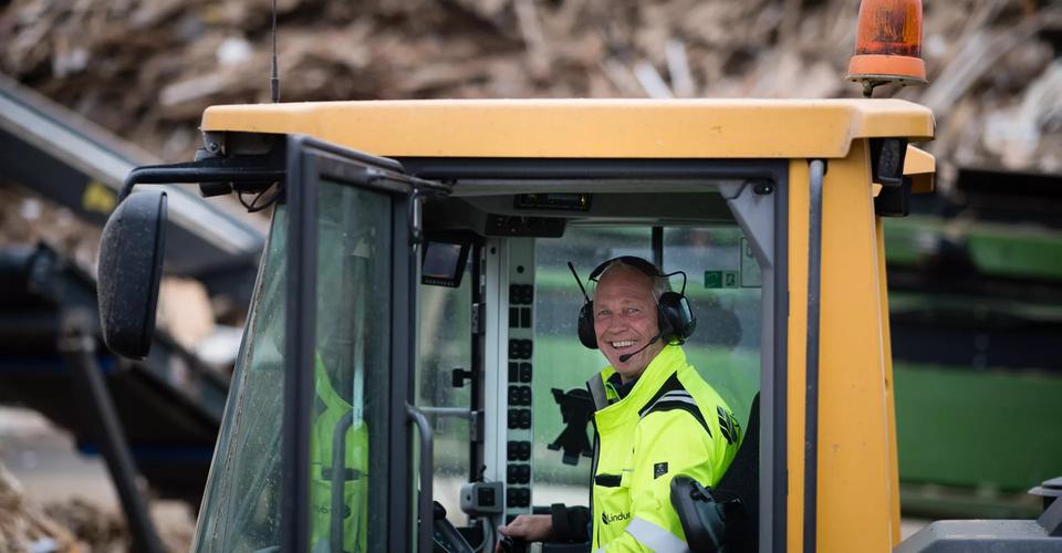 Mann i gravemaskin smiler