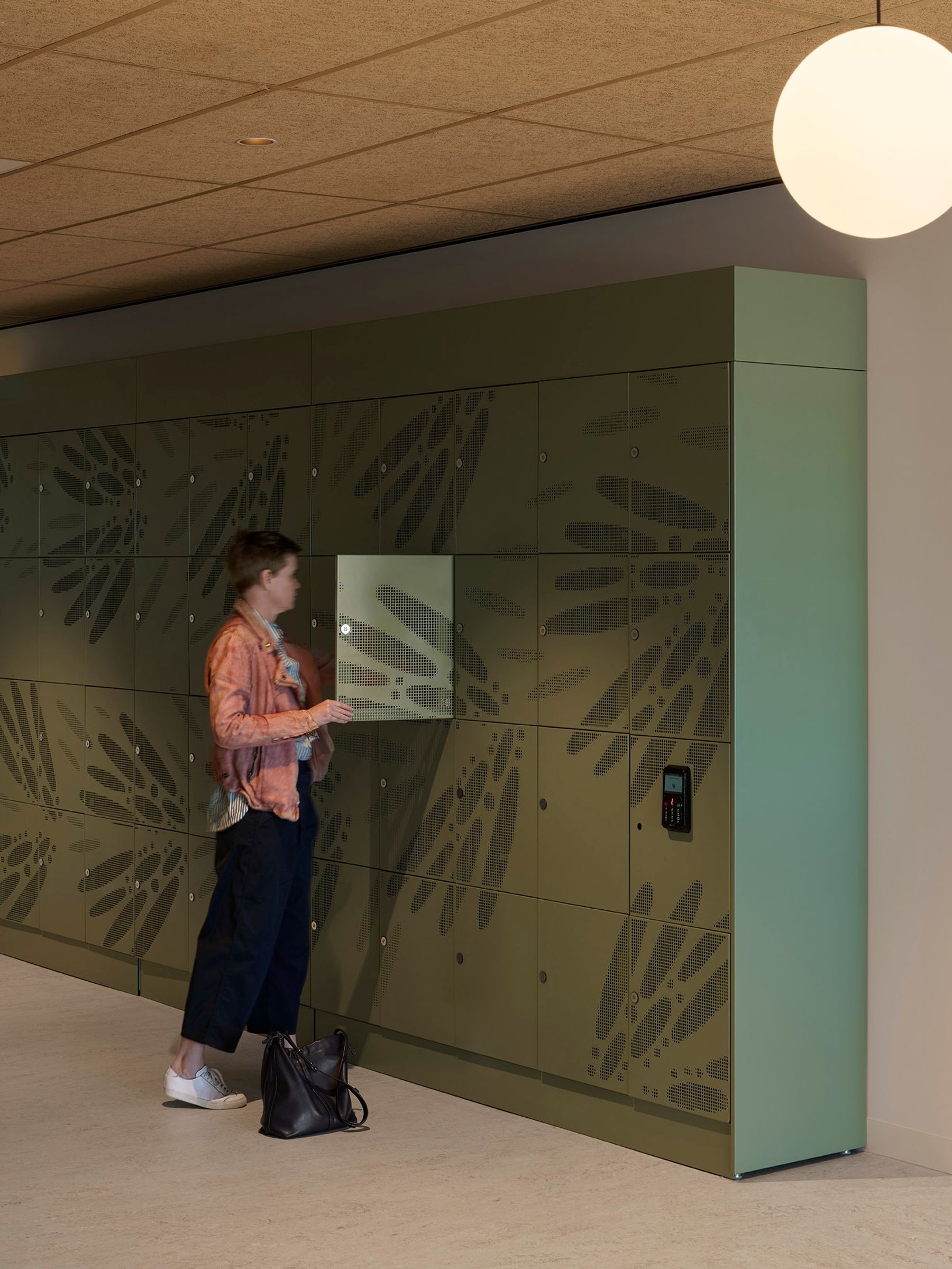 Person opening a green locker with artwork across the front. 
