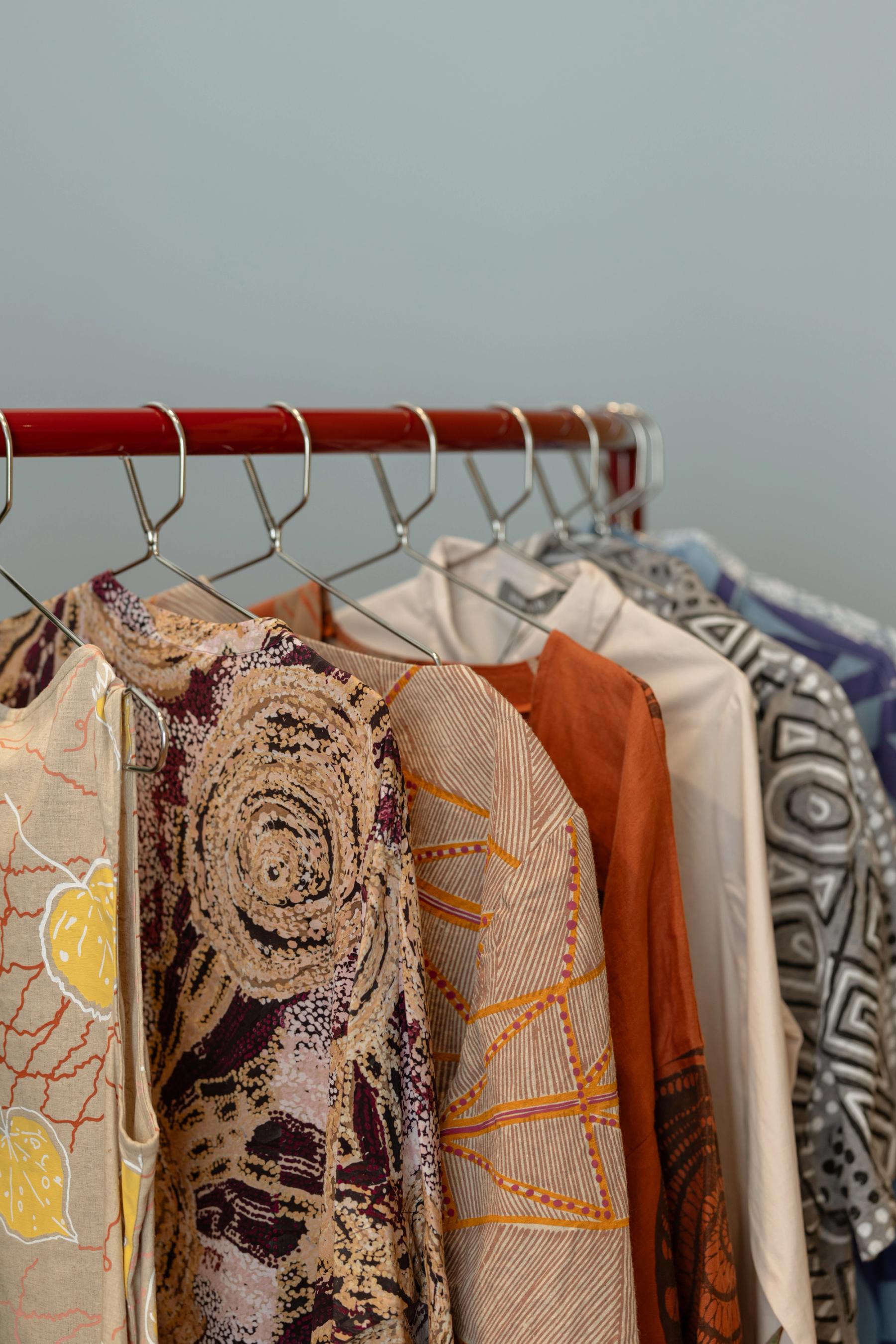 Clothing by Indigenous creators hanging on a clothing rack.