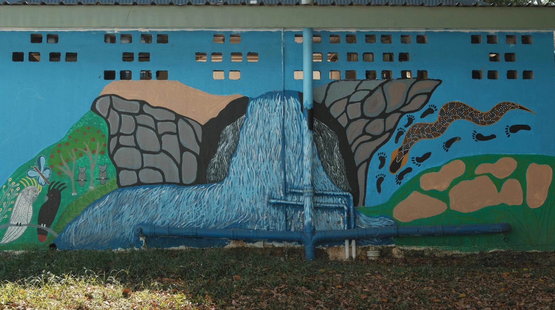 Colourful mural of a waterfall over a rocky landscape, featuring birds, a buttery, a snake and several footprints