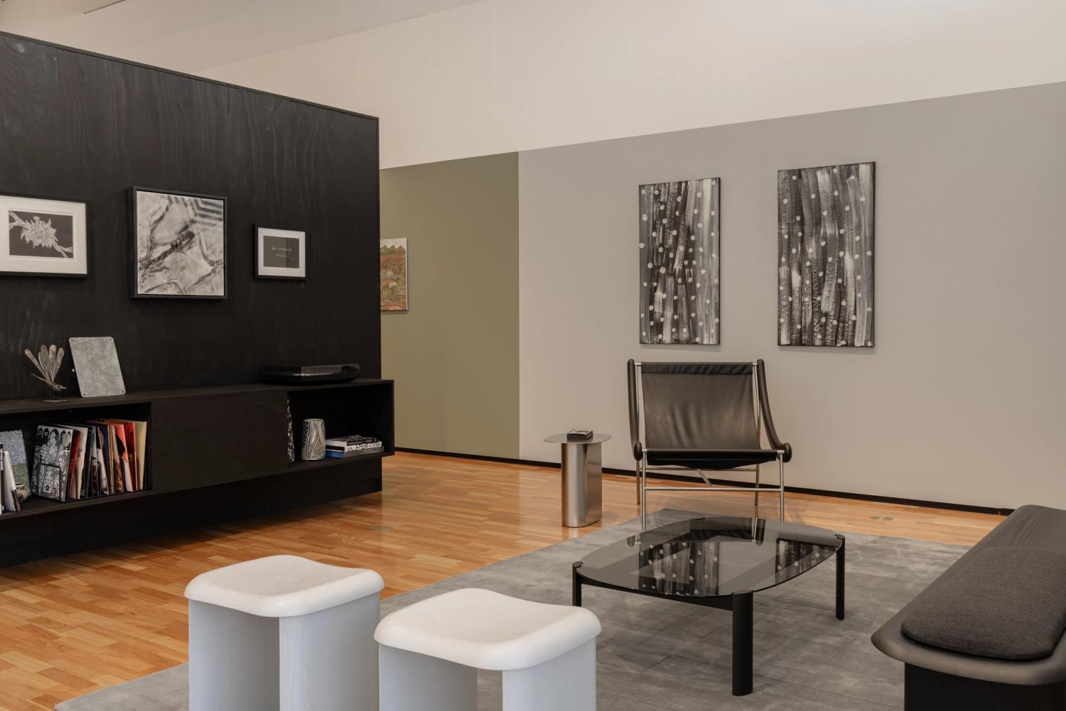 Black-and-white living room with various chairs, coffee table, artwork and filled shelves.