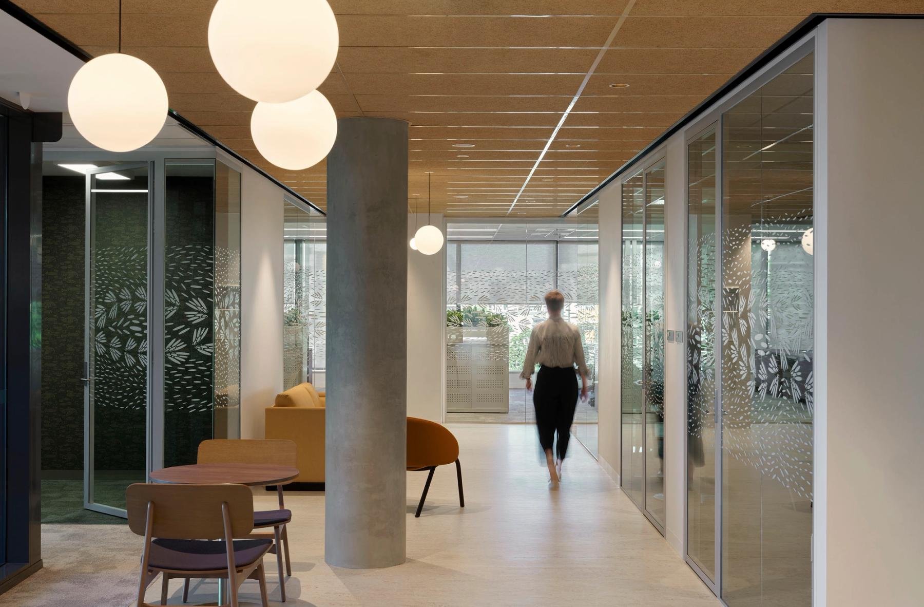 Person walking through office space, highlighting the custom artwork glazing decal on glass walls and doors, representing bird movement.