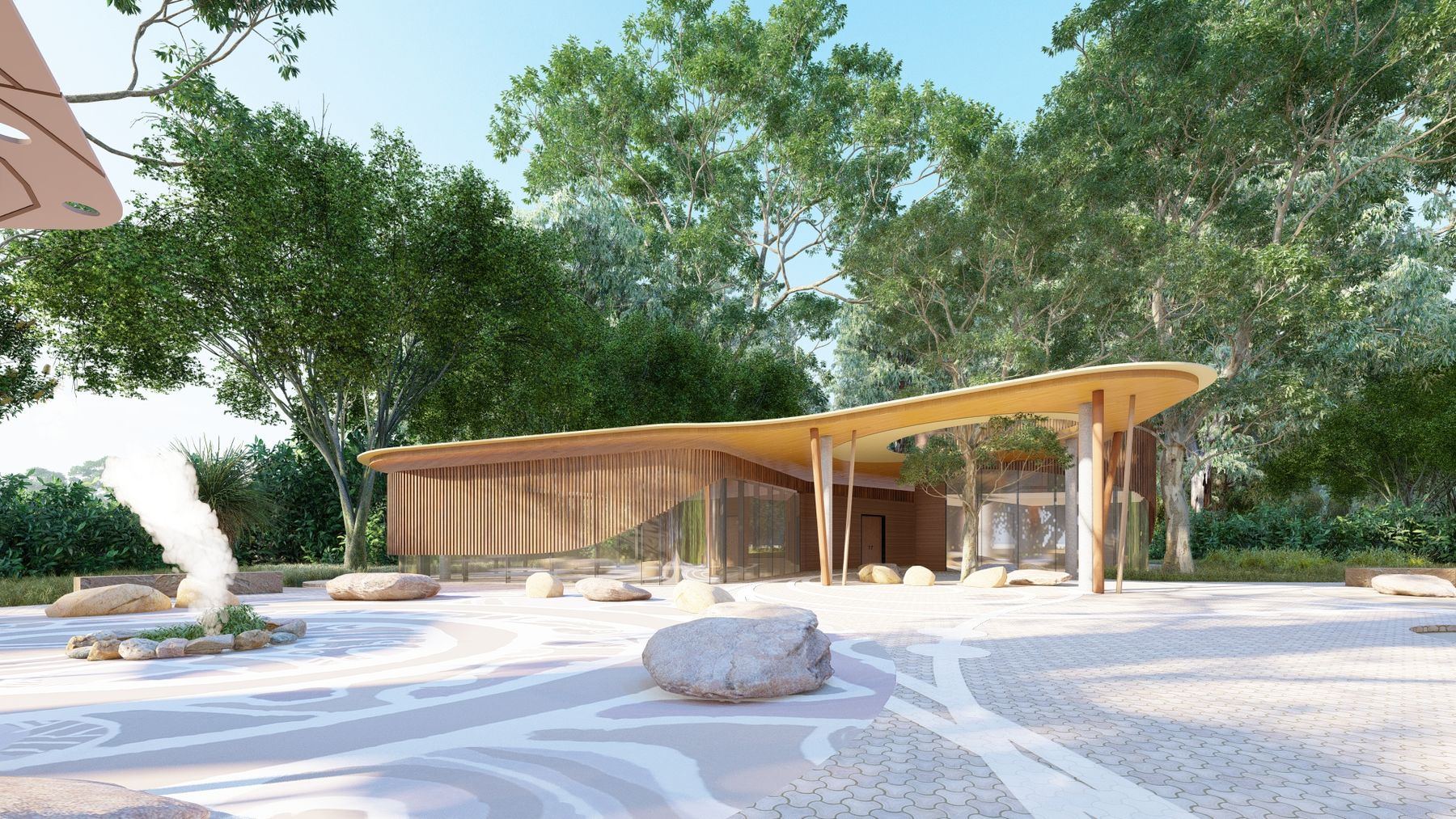 Curved timber building with glass walls, surrounded by trees and sandstone rocks in a patterned courtyard.