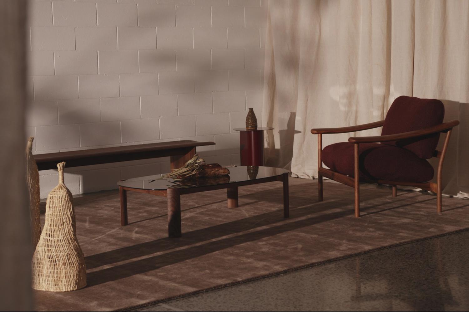 A living room space featuring Elements by Blaklash furniture, including a lounge chair, side table, coffee table, bench, rug and woven pieces
