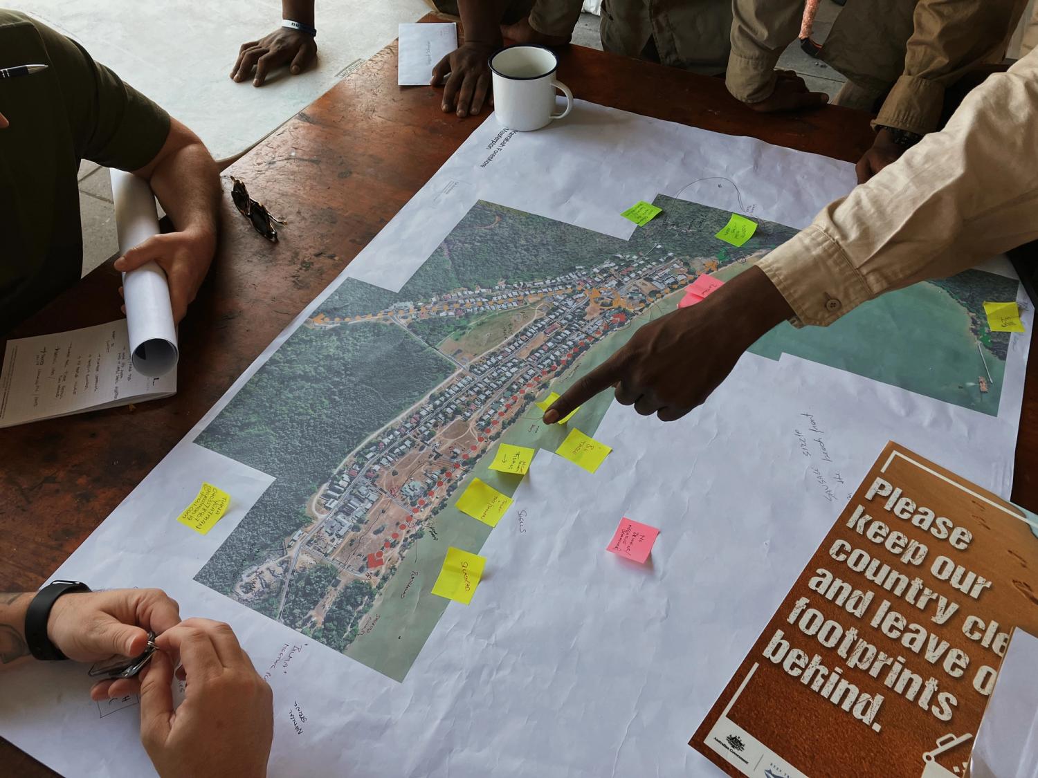 Hands point at a revitalisation plan on a wooden table