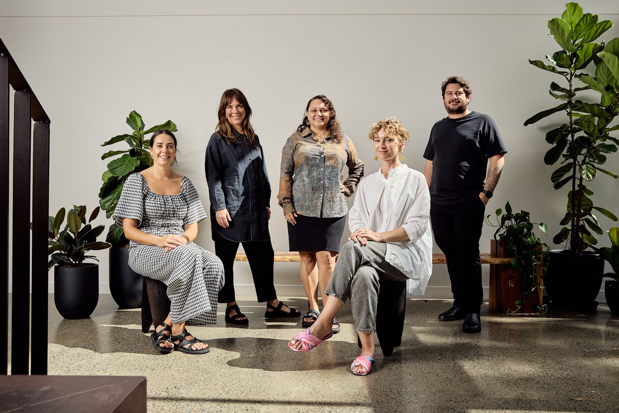 Willie Weston and Blaklash team sit and stand for a group shot against a white wall, with plants in the backgroun