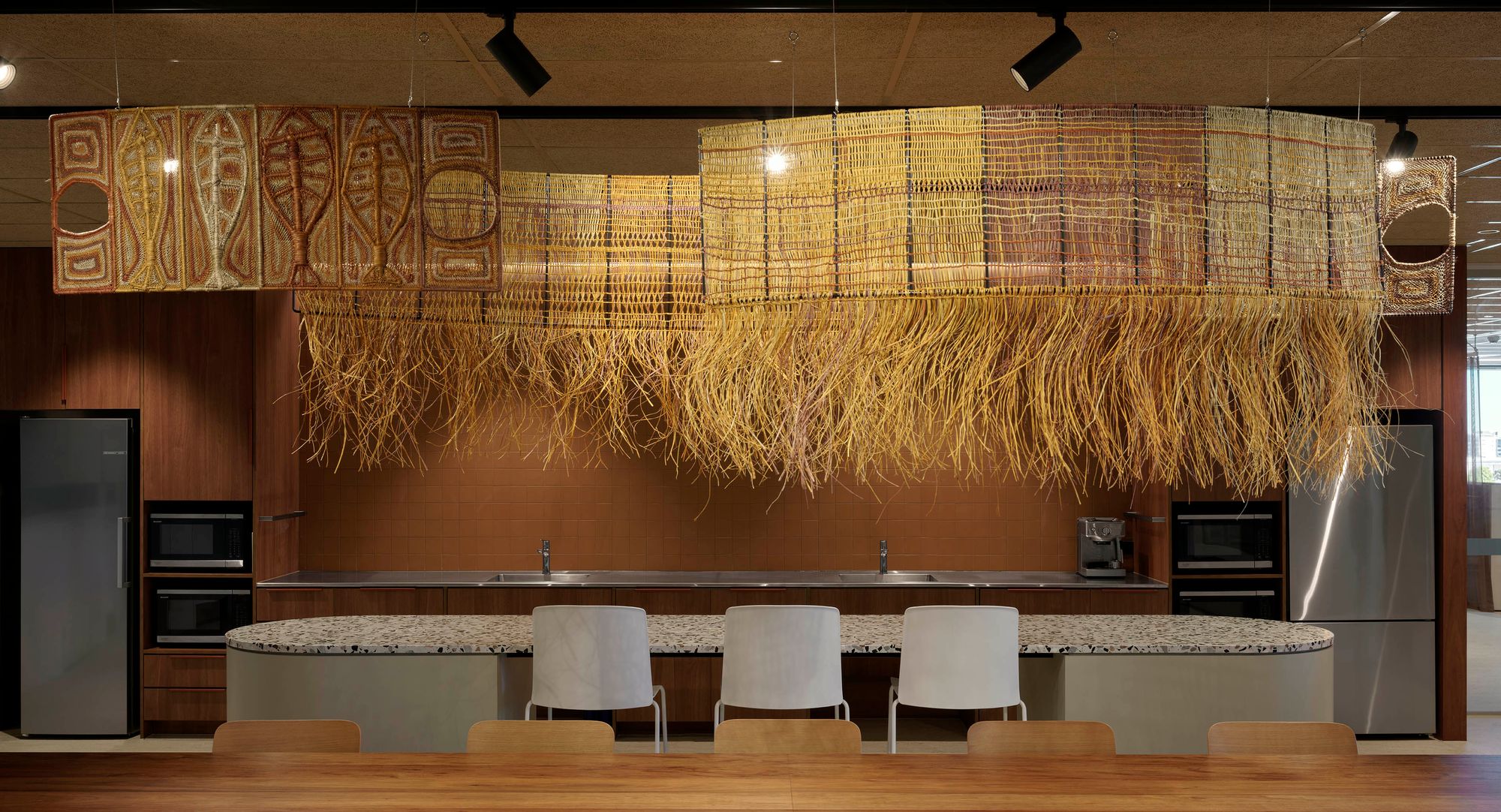Woven pendants hanging above a kitchen space in warm tones