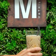 Un cocktail davanti all'insegna M di Mathilda sulla parete verde