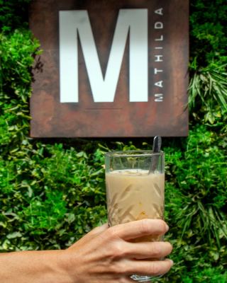 Un cocktail davanti all'insegna M di Mathilda sulla parete verde