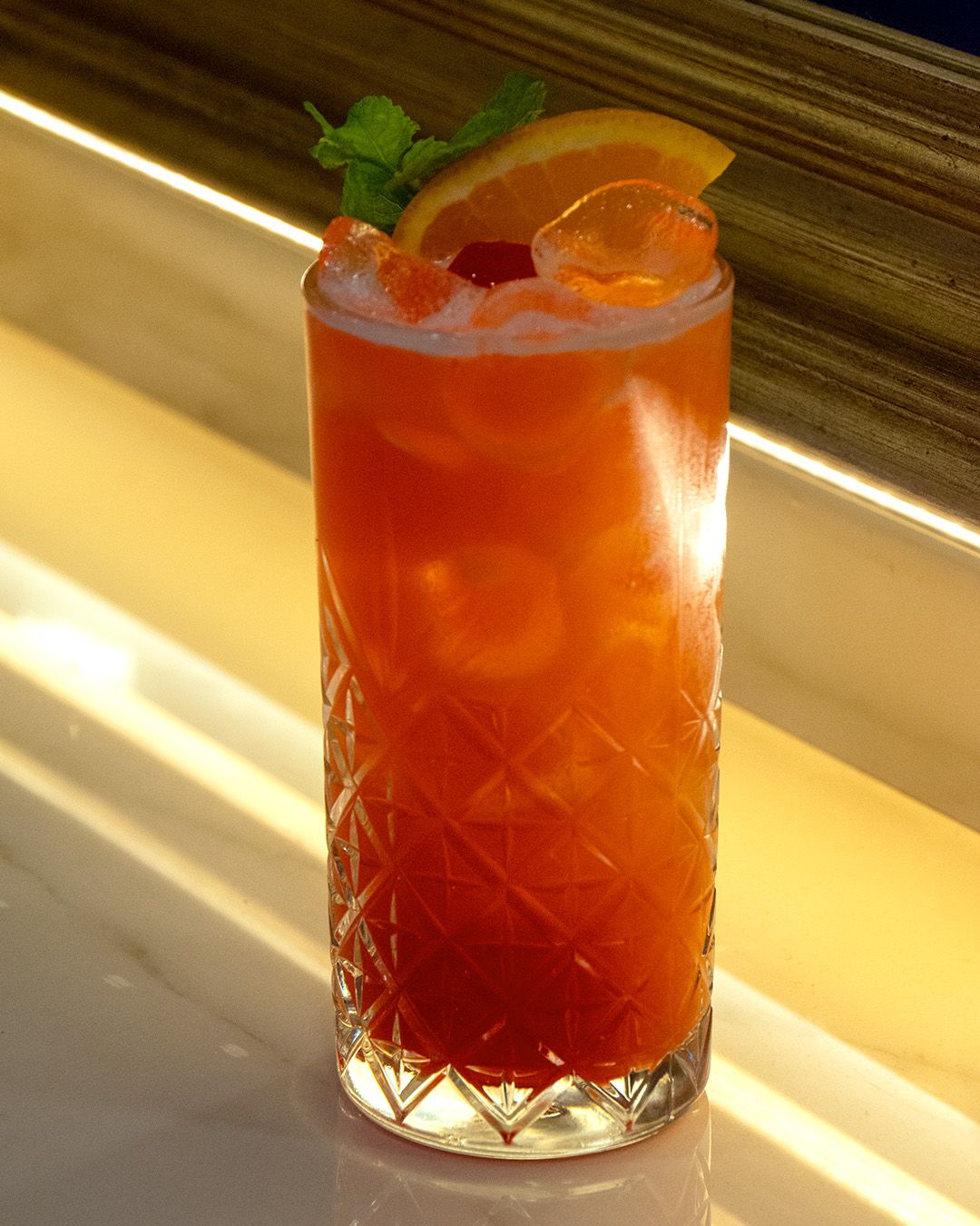 Cocktail all'arancia con menta sul bancone illuminato