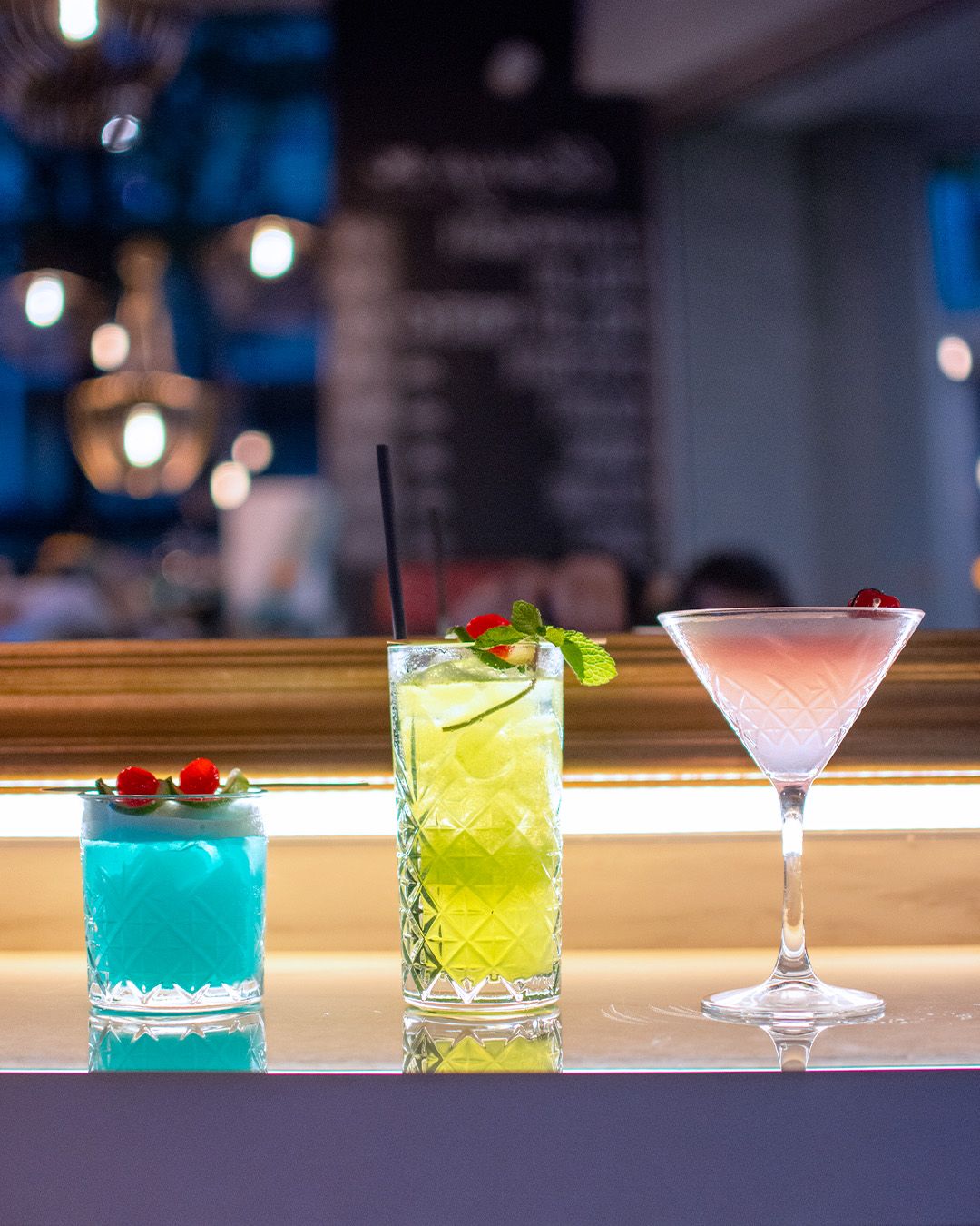 Tre cocktail colorati allineati sul bancone