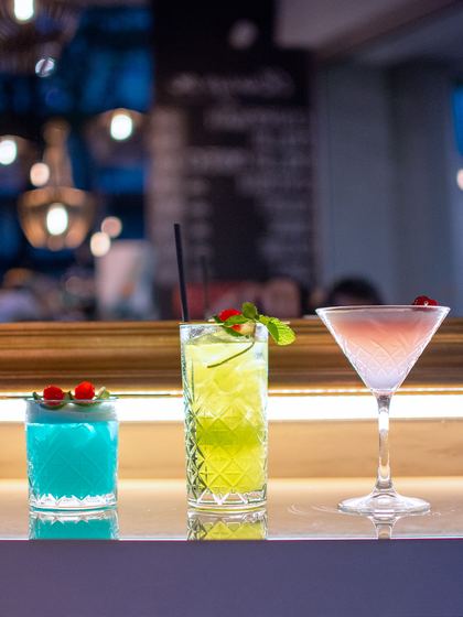 Tre cocktail colorati allineati sul bancone