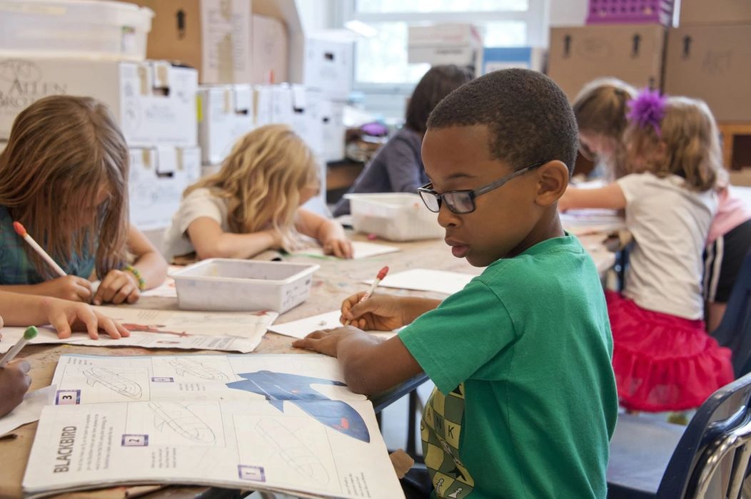 school children sitting at table writing