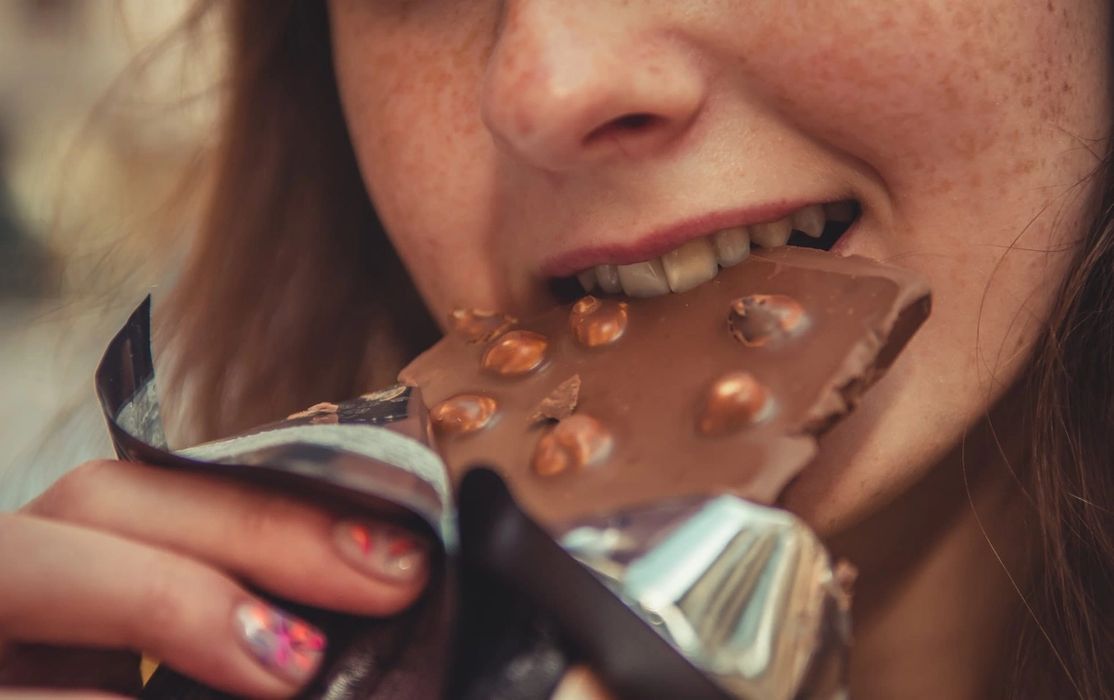 Woman eating chocolate bar with nuts