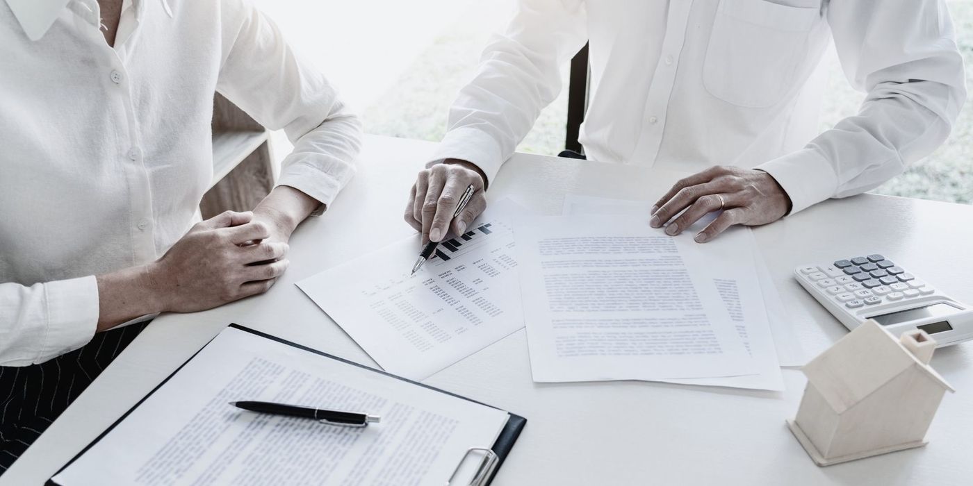 Person signing a real estate contract document at a desk
