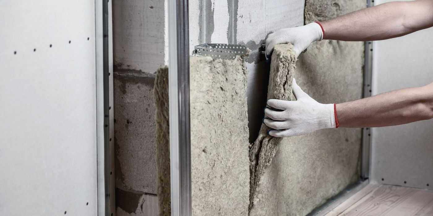 Construction worker installing thermal insulation on a residential wall during energy renovation