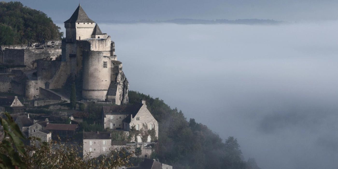 Historic French château de Castelnaud on a misty morning