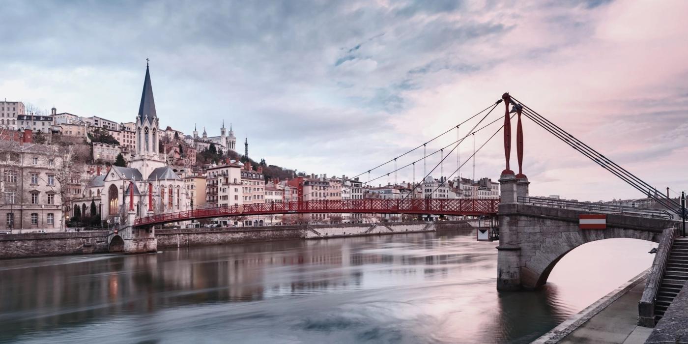 View of church and footbridge accross Saone river, old town during sunset