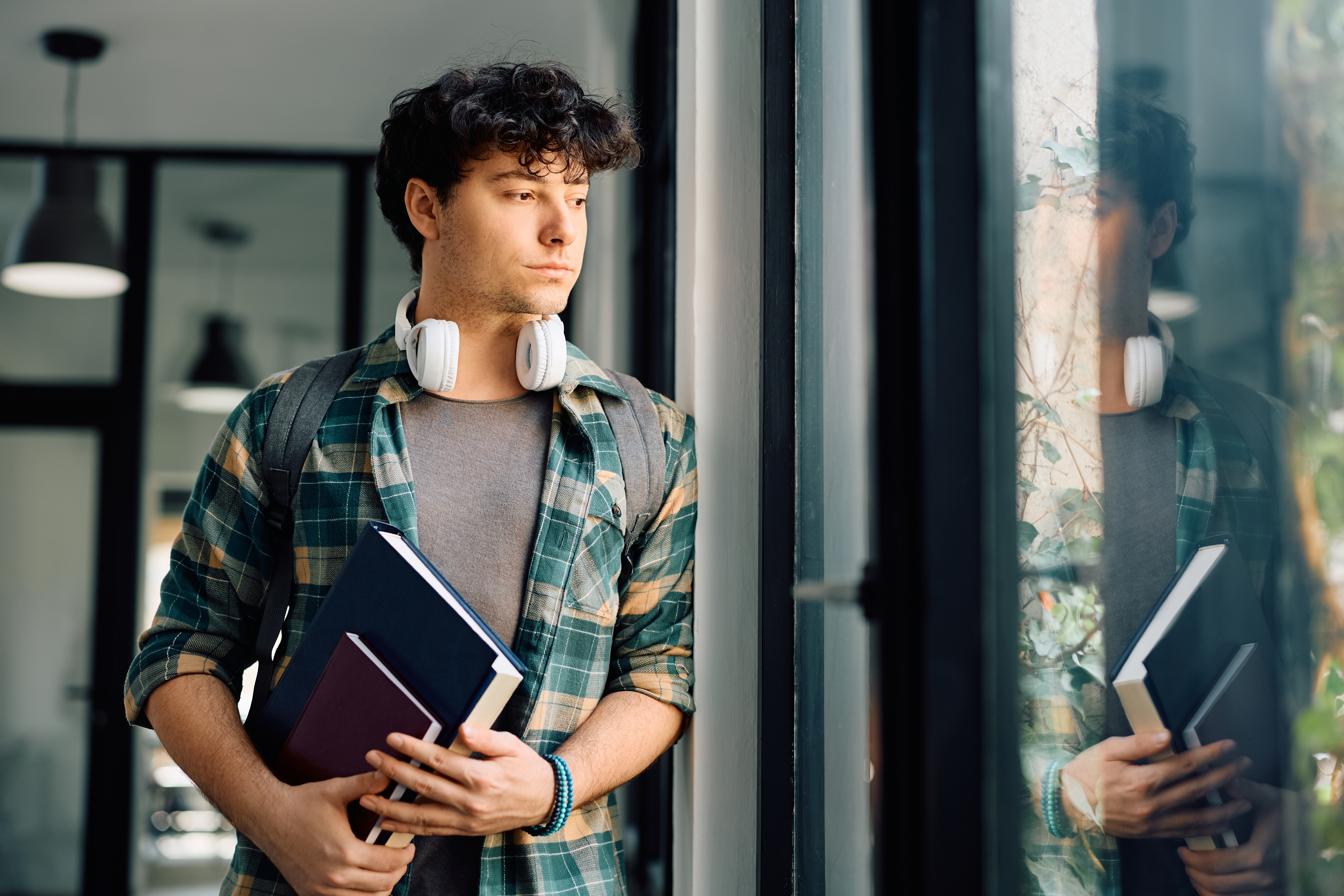 Medical student holding books and looking out a window thoughtfully