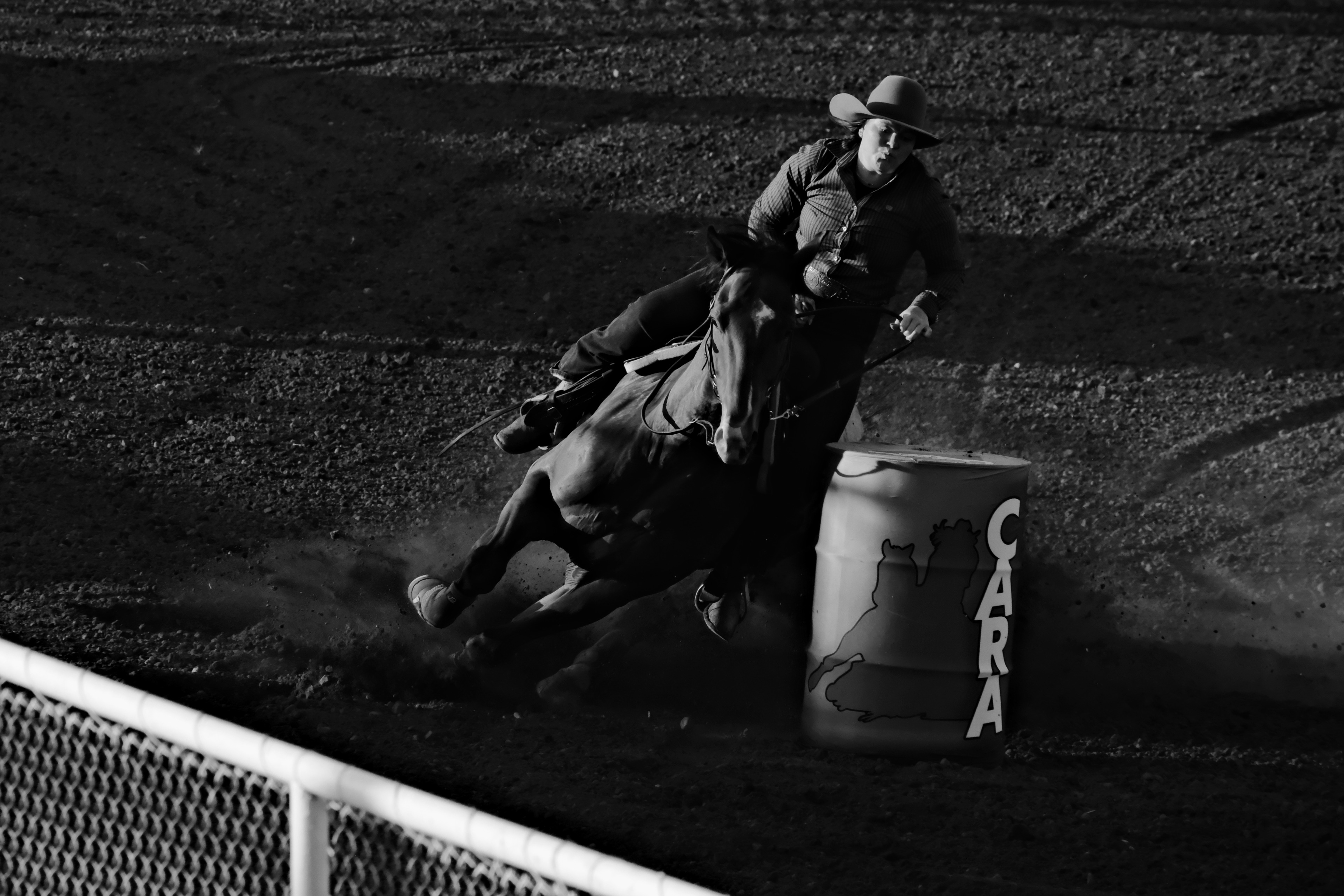 A barrel racer on horseback rounds a barrel at high speed during the Rimbey Rodeo in Alberta.