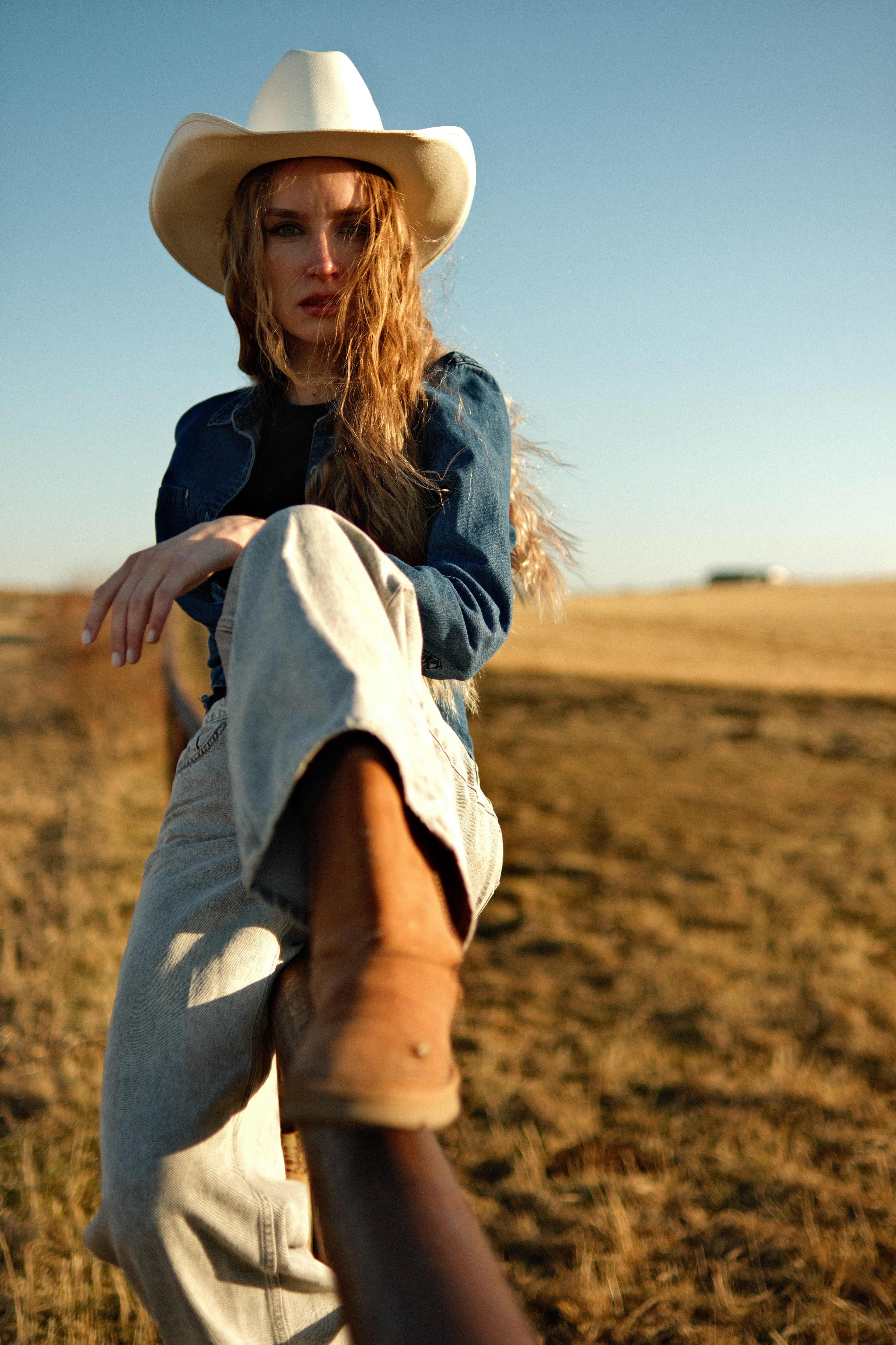 Cowgirl portrait with boot forward, rustic outdoor field background, Cochrane Alberta