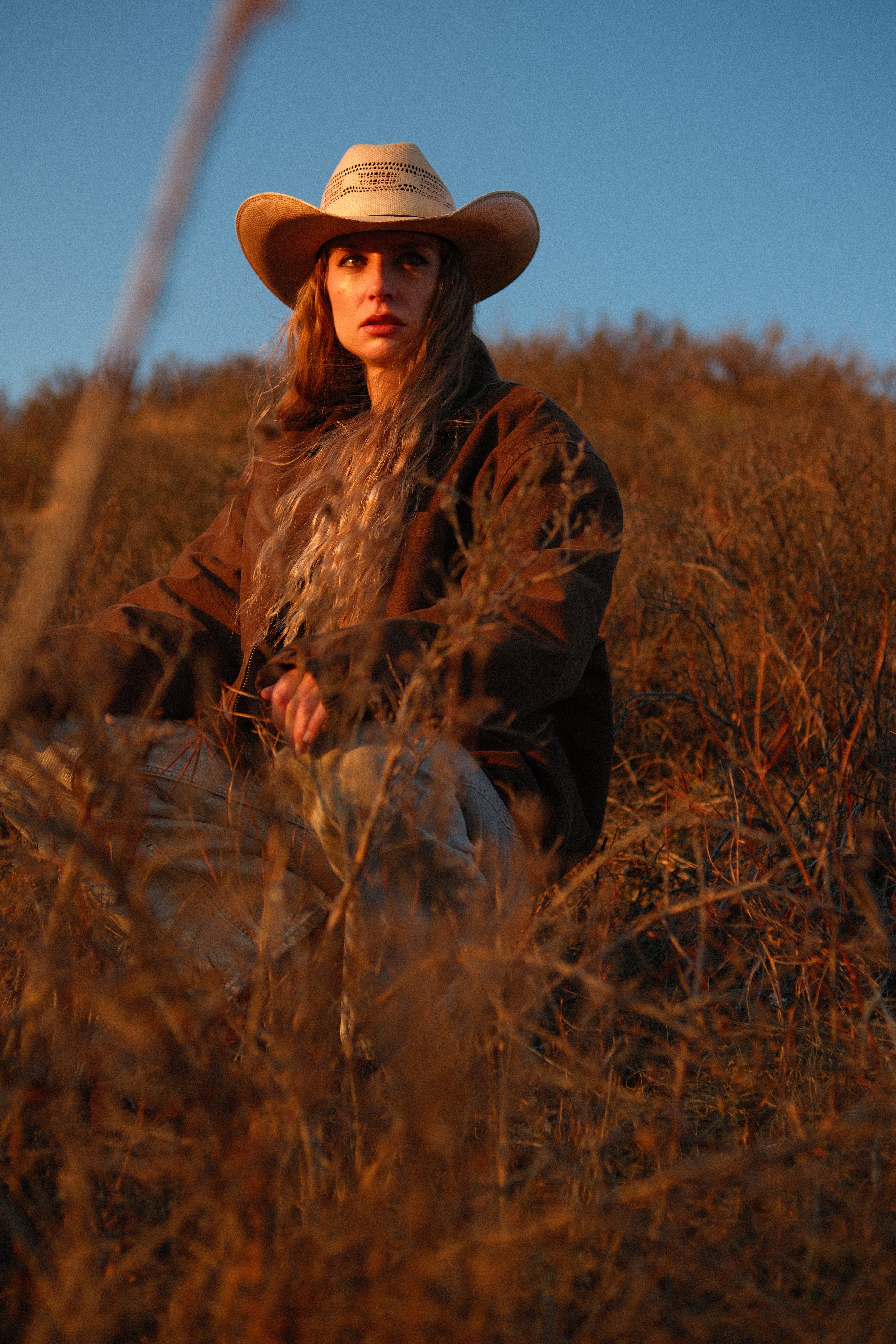 Outdoor portrait of model Mariana sitting in golden fields during sunset, natural light photography