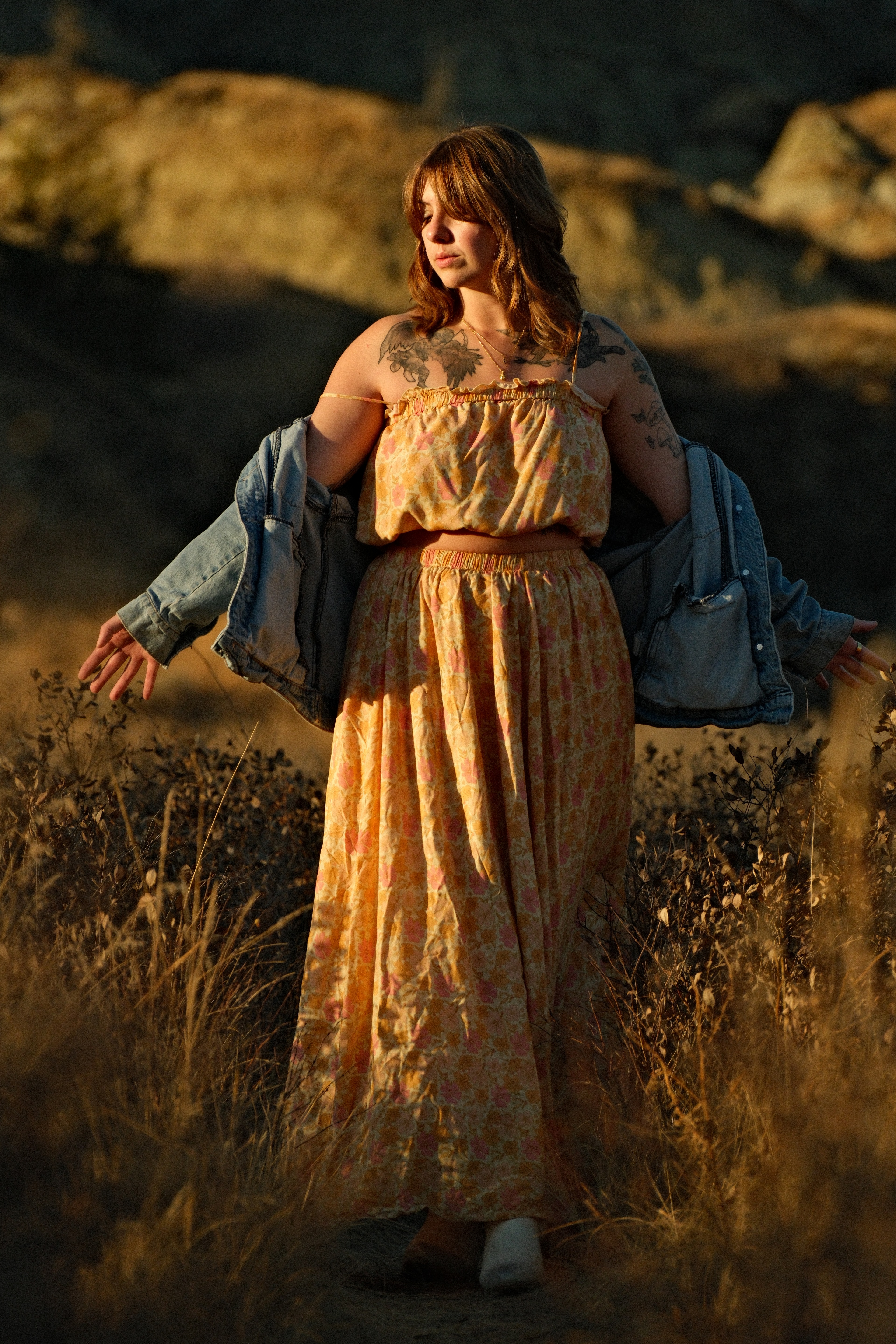 Rachel Peters wearing a flowing yellow dress with denim jacket in the sunlit badlands of Dry Island Buffalo Jump Provincial Park, Alberta