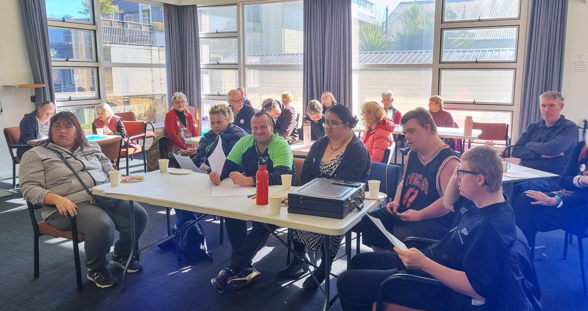 Group of people sitting in a sunny room.