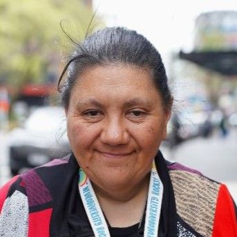 Larni-Jean is wearing a red top with abstract shapes. she is smiling.