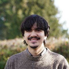 Man with short hair smiling with a sweater