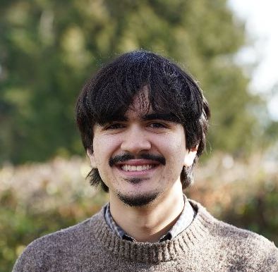 Man with short hair smiling with a sweater