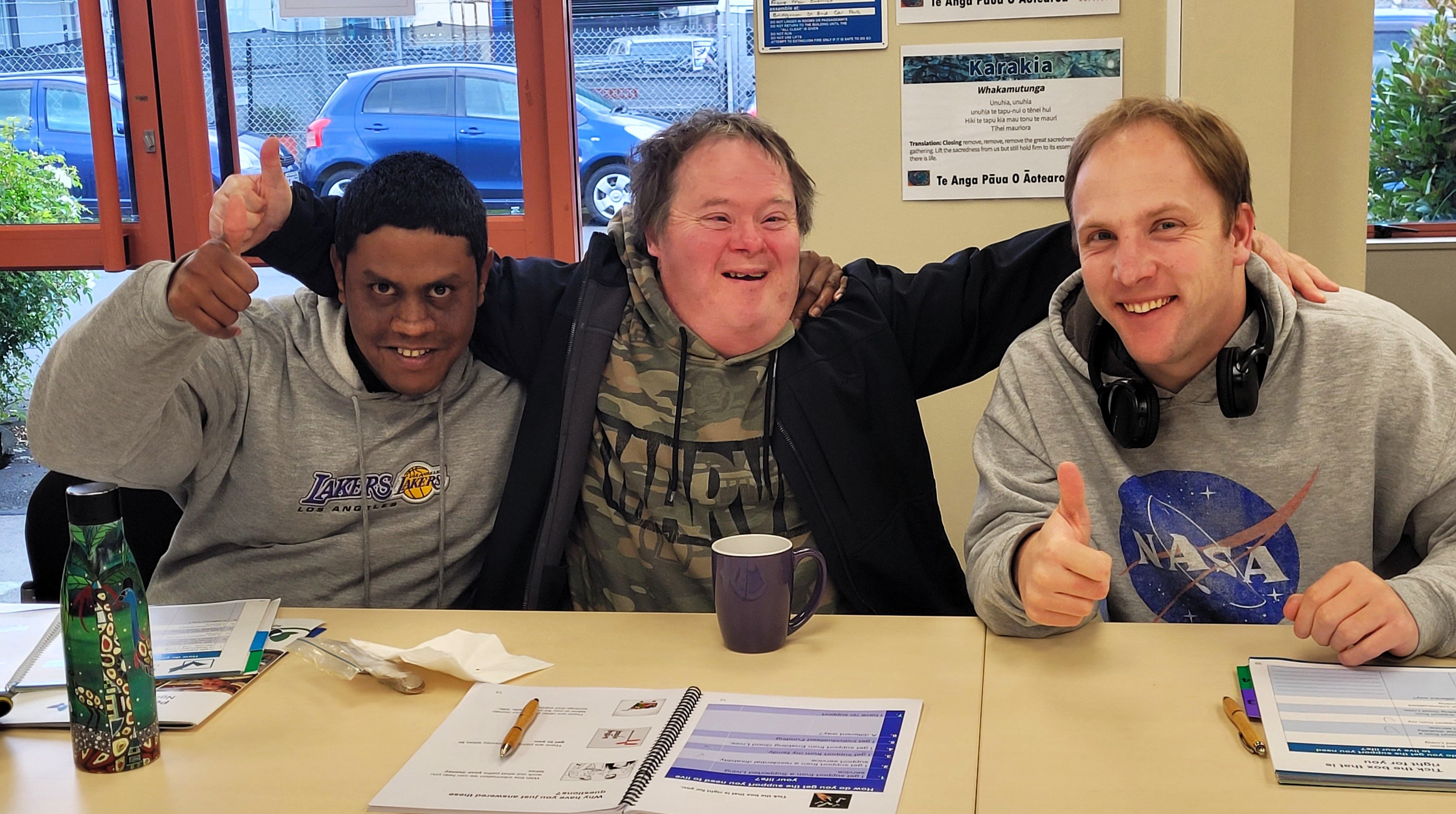 three members smiling at the camera at a meeting.