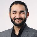 Maninder Hooda smiling in a suit.