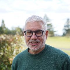 Gary is wearing glasses and has grey hair.