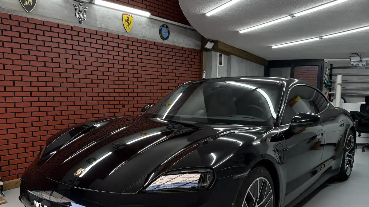 Siyah Porsche Taycan'ın kaputunda ışık altında yüzey kontrolü