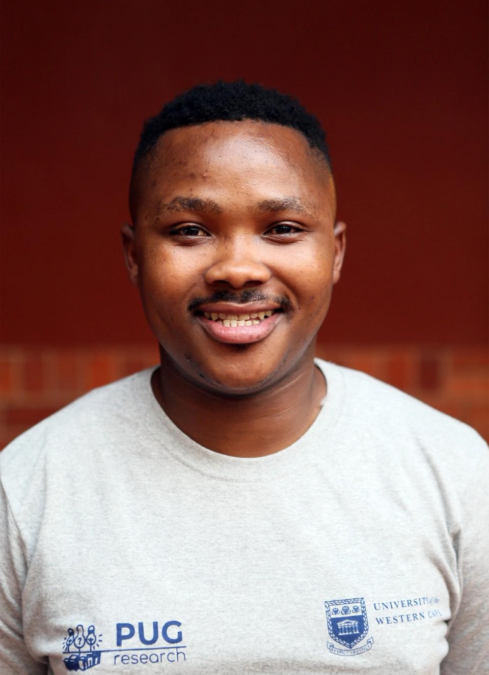 a man wearing a pug research shirt smiles for the camera