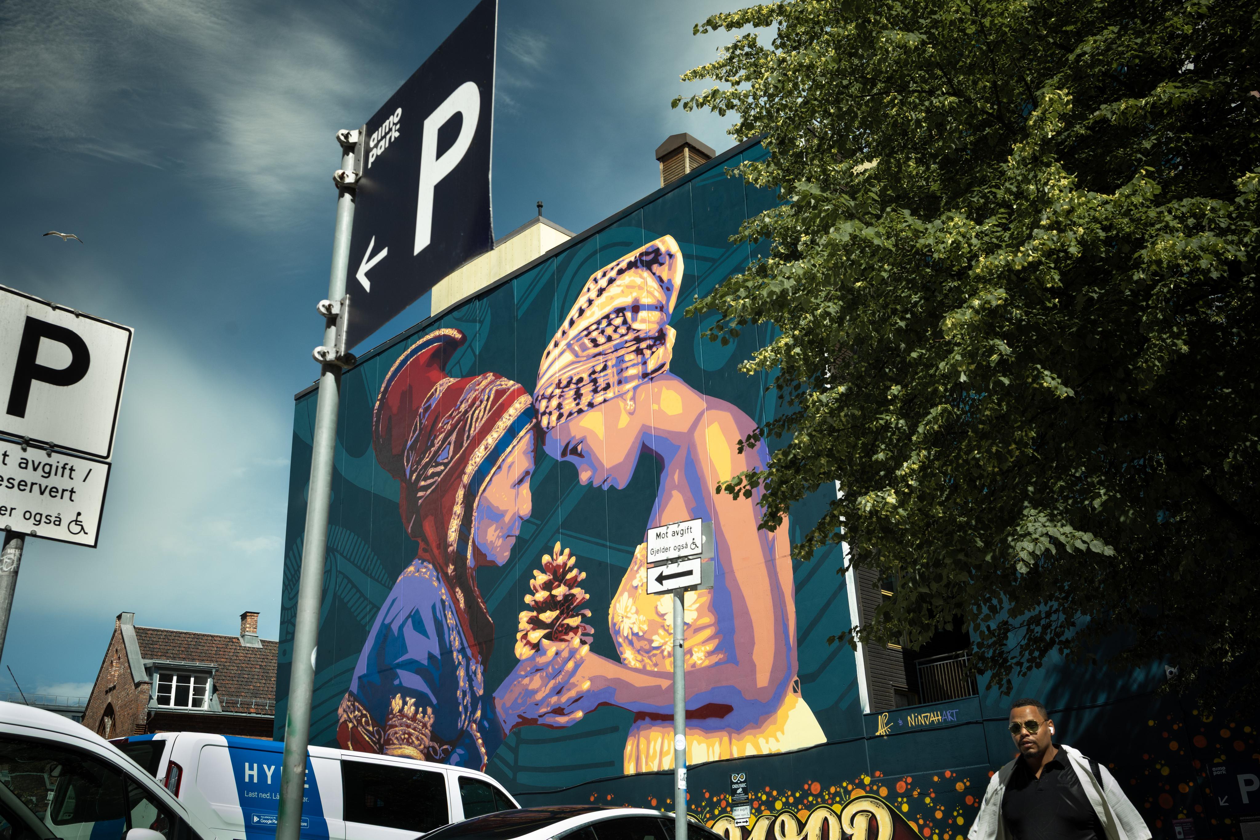 a man is walking past a large mural on the side of a building .