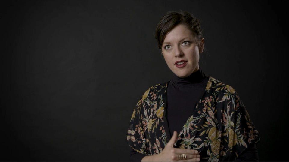 A woman wearing a black turtleneck and a floral shirt.