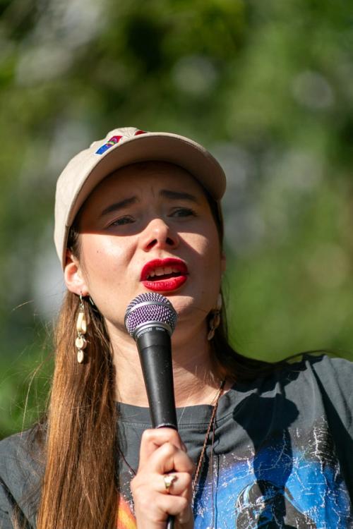 a woman wearing a hat is singing into a microphone