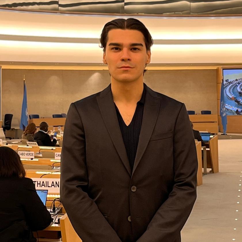 a man in a suit stands in front of an assembly room
