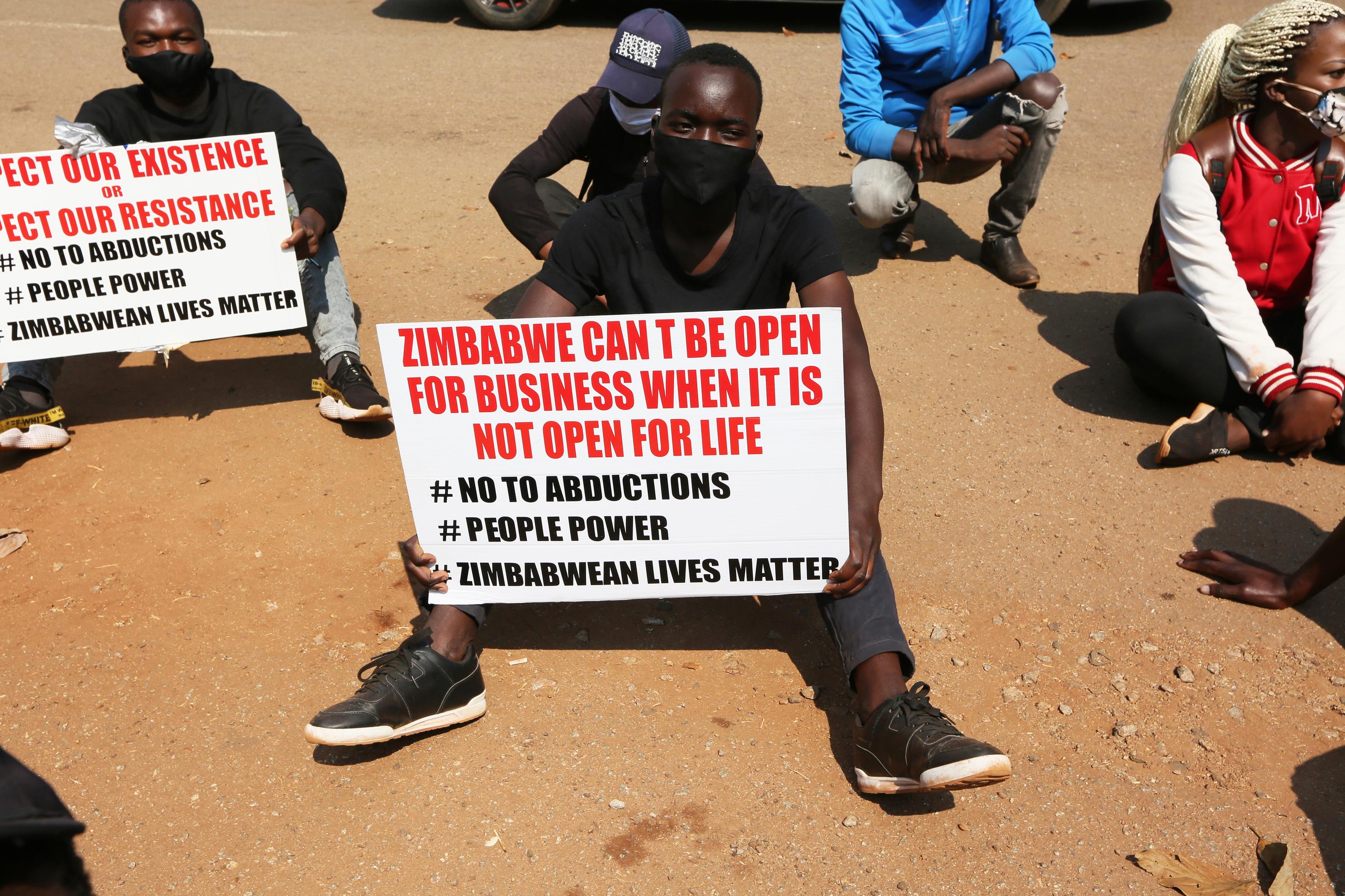 Student activist holds a banner with the text "Zimbabwe can`t be open for business when it is not open for life. #No to abductions, #People power, #Zimbabwean lives matter
