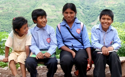 Four schoolchildren sitting on a bench.