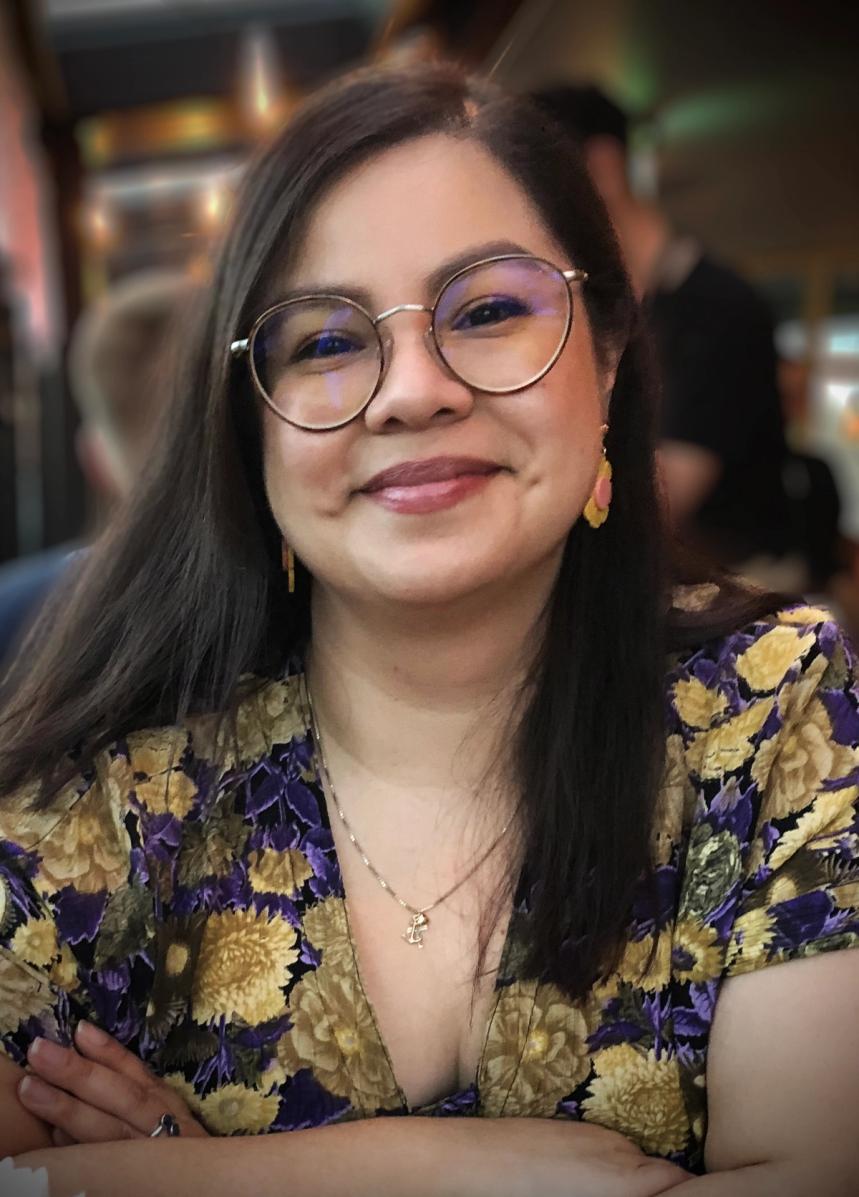 a woman wearing glasses and a floral shirt is smiling for the camera .