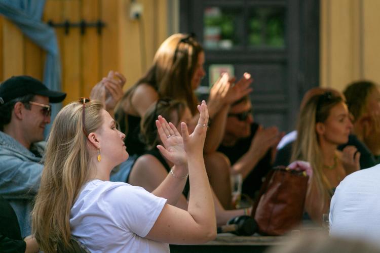 a group of people are sitting at a table clapping their hands .