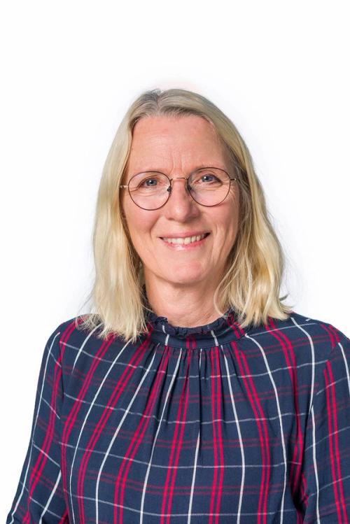 a woman wearing glasses and a plaid shirt smiles for the camera