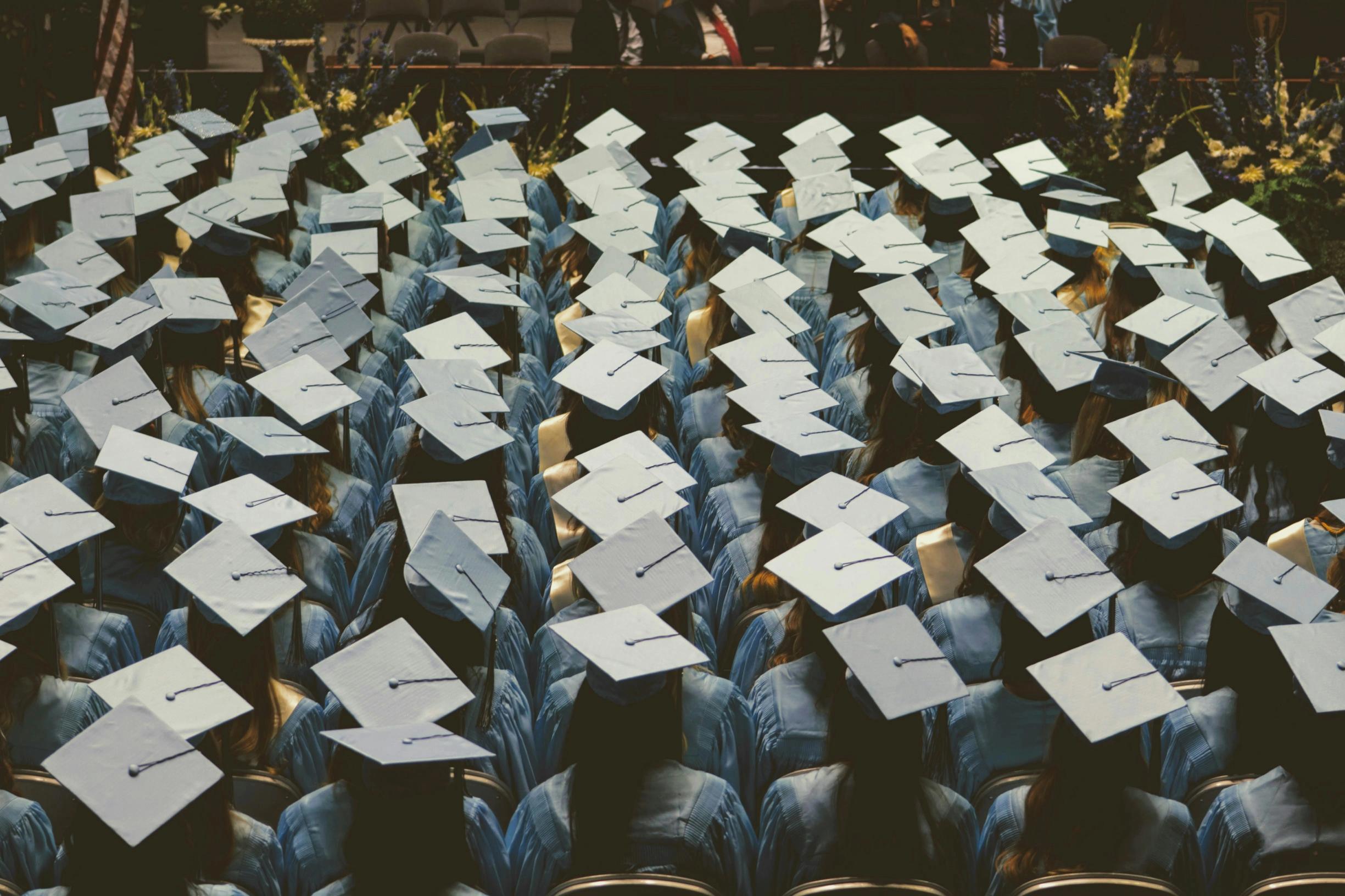 a row of graduation caps are sitting on top of each other in a stadium .