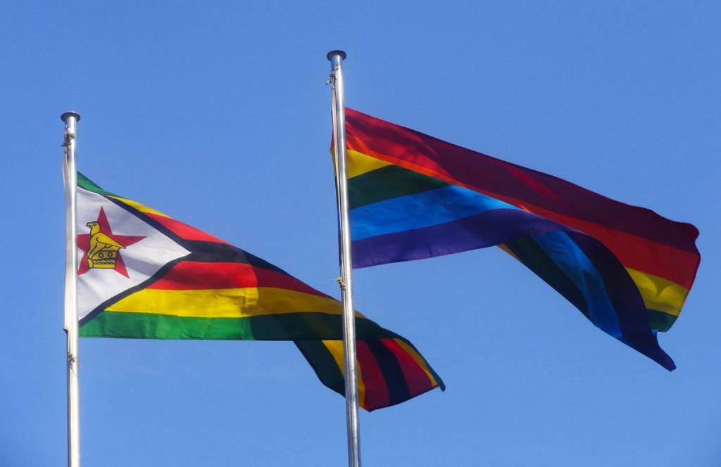 Regnbueflagget og det zimbabwiske flagget som blafrer i vinden