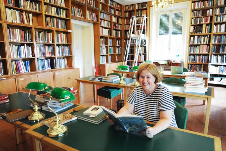 a woman is sitting at a desk in a library reading a book .